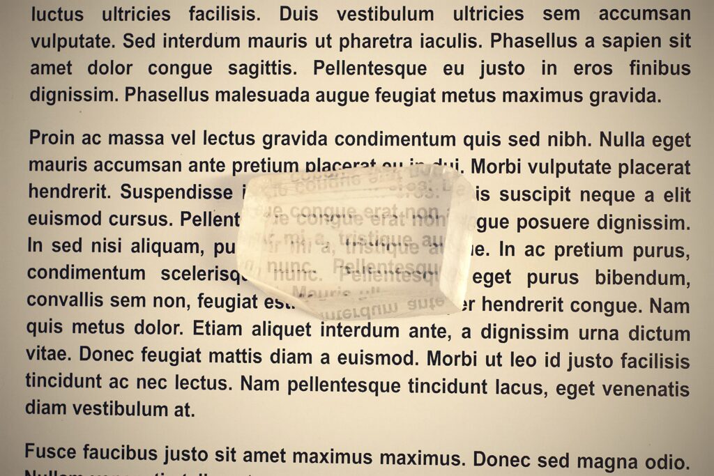 A calcite crystal doubling the printed text beneath it, the birefringence a Viking sunstone depends on