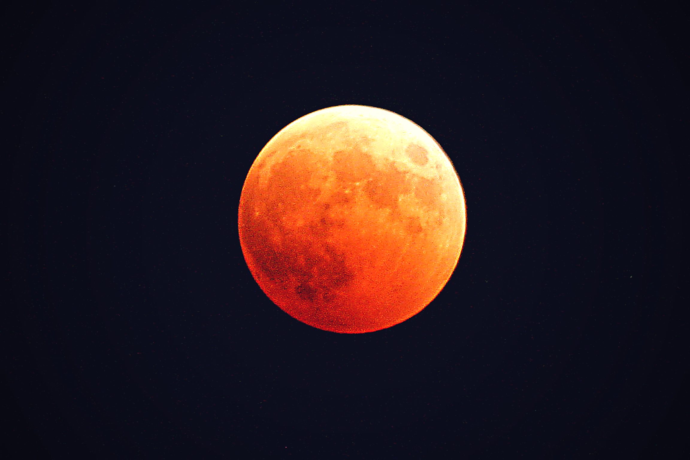 A blood moon during a total lunar eclipse, the moon glowing red against the night sky